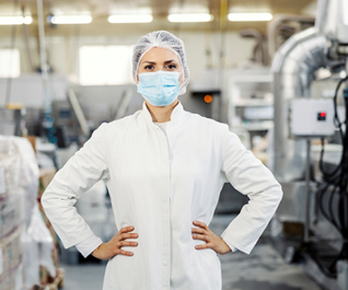 Lab worker with mouth mask and hands on her hips