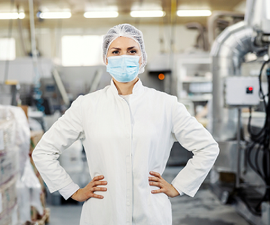 Labmedewerkster met mondmasker en handen in haar zij