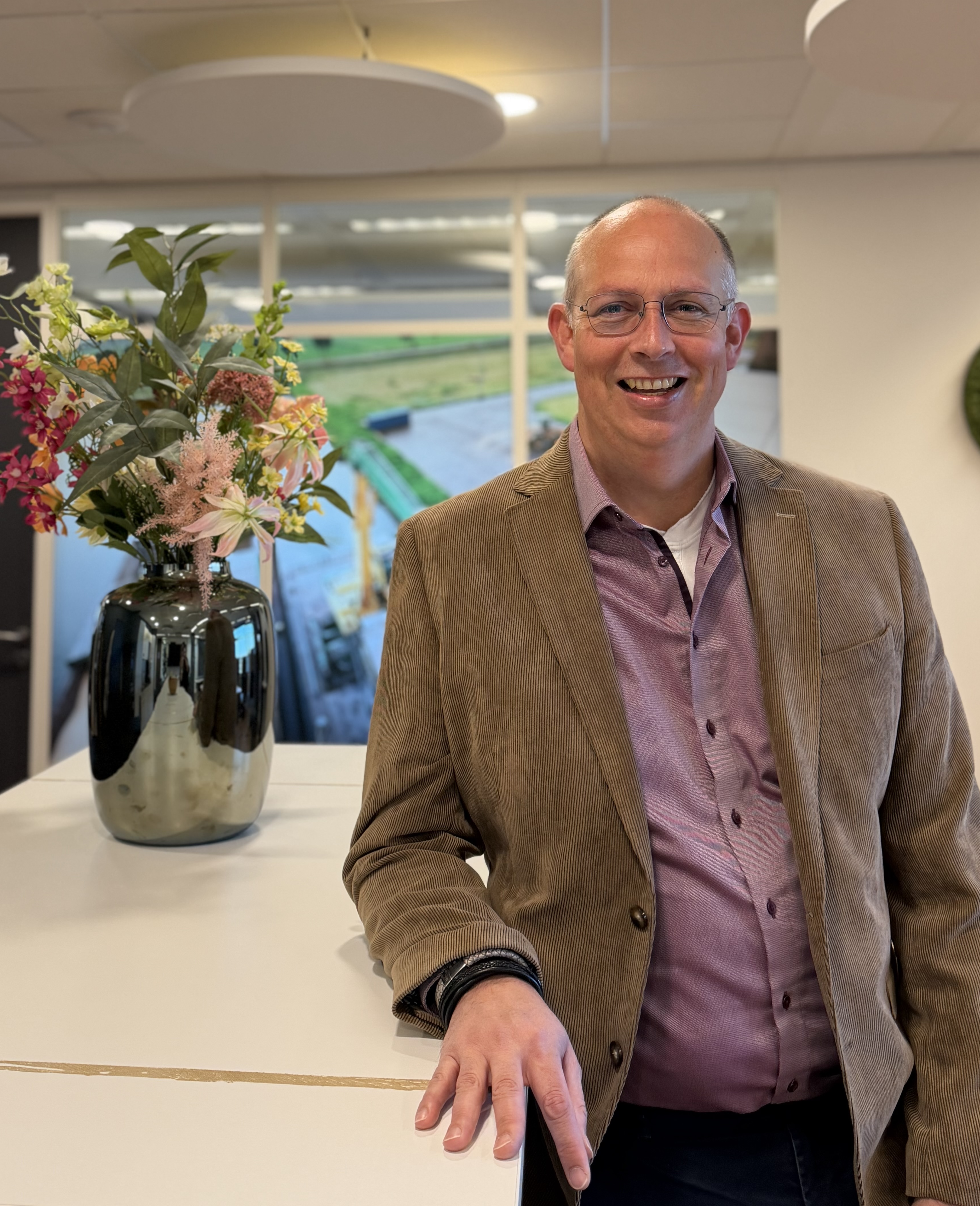 man op kantoor, staand bij een tafel